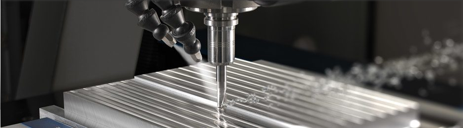 Zu sehen ist die Bearbeitung eines Frästeils mit einer CNC-Fräse. Zwei Düsen besprühen dabei das Werkstück zur Kühlung mit einer Flüssigkeit